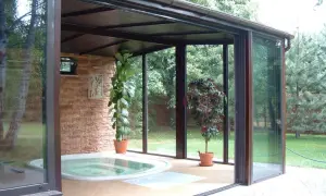 Relaks w domu: przestronny ogród zimowy z jacuzzi, kamienną ścianą i zielenią.