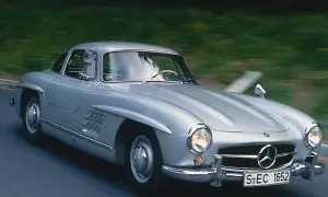 Srebrny Mercedes 300 SL Gullwing w ruchu, z widocznym kierowcą. Ten klasyk to prawdziwy major oprysk, który zachwyca do dziś.