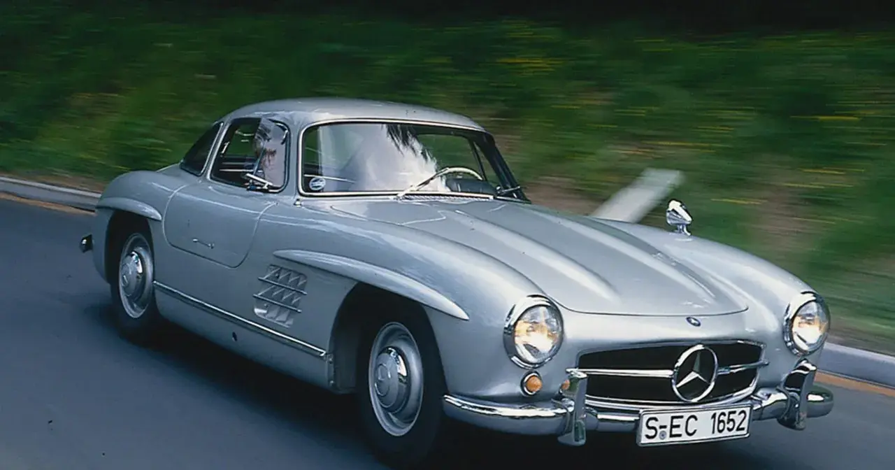 Srebrny Mercedes 300 SL Gullwing w ruchu, z widocznym kierowcą. Ten klasyk to prawdziwy major oprysk, który zachwyca do dziś.