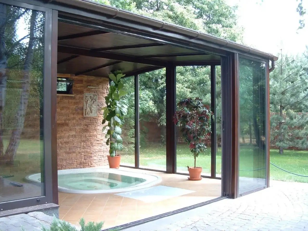 Relaks w domu: przestronny ogród zimowy z jacuzzi, kamienną ścianą i zielenią.